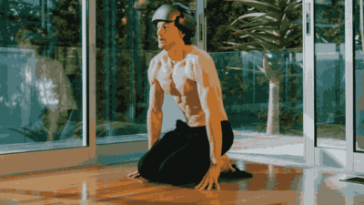 Man wearing a helmet kneels on the floor in front of glass doors, appearing to practice breathing exercises related to Byran Johnson Hyperbaric Chamber.
